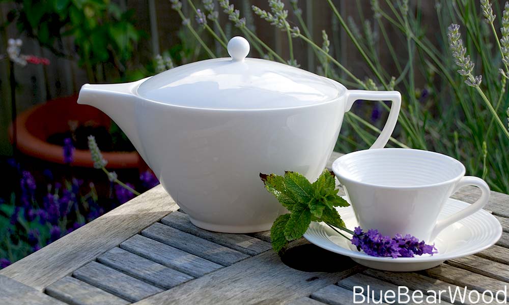 Teapot And Teacup on a garden table with lavender in the background ready for Fresh Lavender Tea