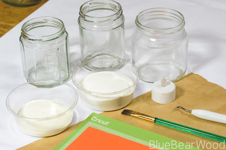 Empty Jam Jars, White Glue, Paint Brush & Window Cling Used To Make DIY Frosted Luminaries